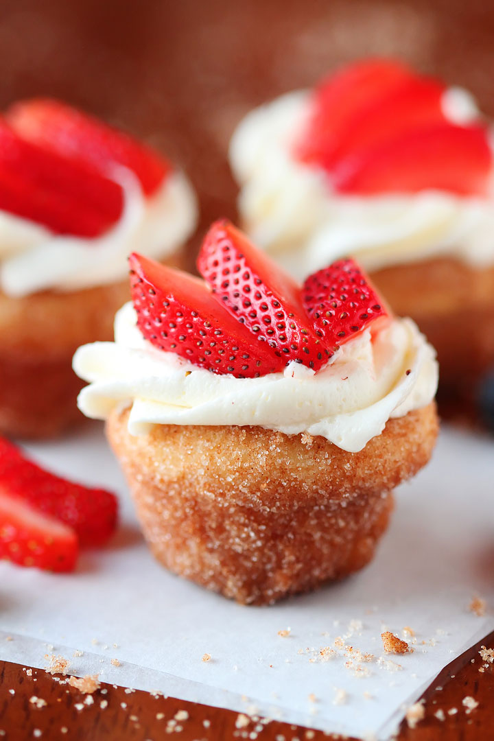 Strawberry Shortcake Doughnut Muffins. These are like little bites of HEAVEN. A muffin that tastes like a doughnut, dunked in brown butter and rolled in cinnamon sugar for a sweet, crunchy crust. Then topped with buttercream frosting and fresh cut strawberries. Amazing.