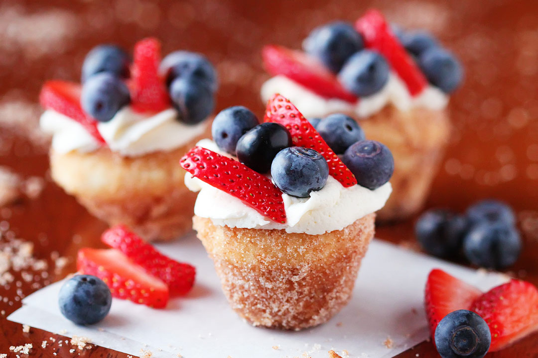 Strawberry Shortcake Doughnut Muffins. These are like little bites of HEAVEN. A muffin that tastes like a doughnut, dunked in brown butter and rolled in cinnamon sugar for a sweet, crunchy crust. Then topped with buttercream frosting and fresh cut strawberries. Amazing.