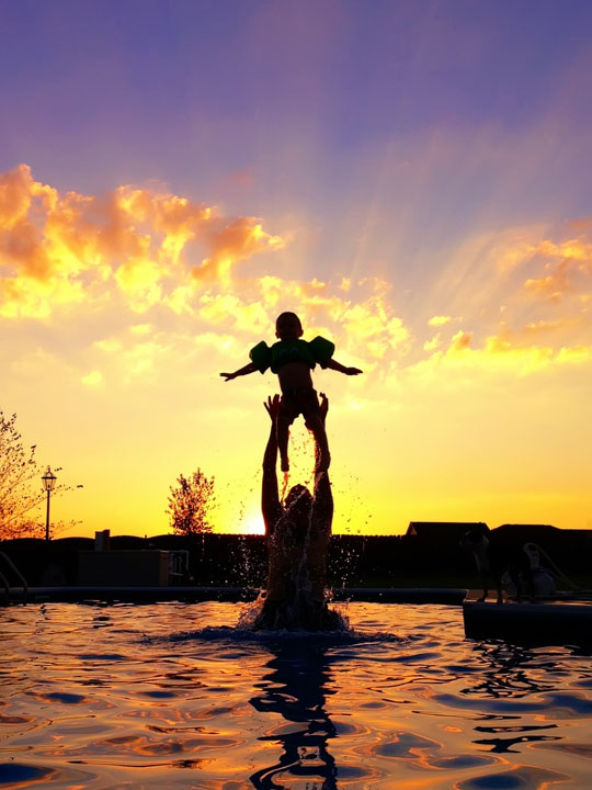 Image of Silhouettes in a Pool in Front of a Sunset
