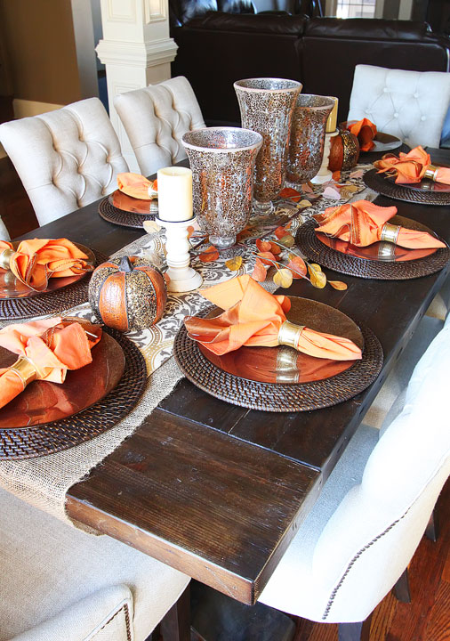 Fall Dining Room Table — Kevin & Amanda The Fall Dining Room Table by Kevin & Amanda features a stunning display of fall kitchen table decor, including a beautiful centerpiece of fresh pumpkins, gourds, and fall foliage. The warm color palette and charming rustic accents create a cozy and inviting atmosphere perfect for gathering with loved ones during the autumn season.