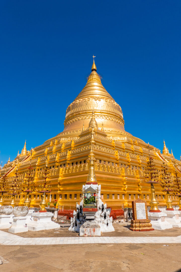 Gold plated Shwezigon Pagoda in Bagan, Myanmar framed by the deep blue cloudless sky.