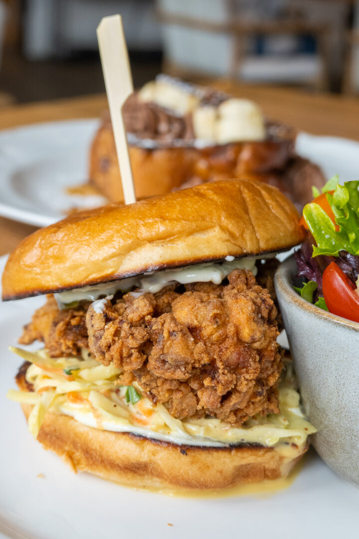 fried chicken sandwich with toasted bun, slaw, and side salad