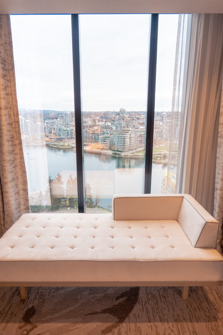 hotel room on a high floor with couch in front of floor to ceiling windows with harbor view