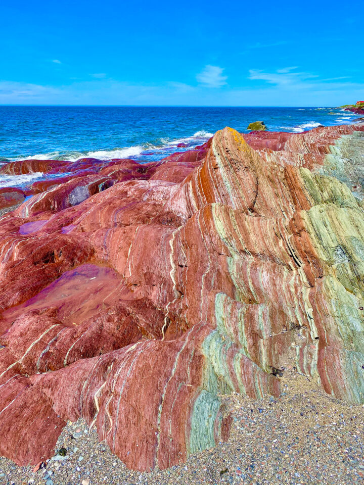 colorful red rock formations on beach in Gaspesie