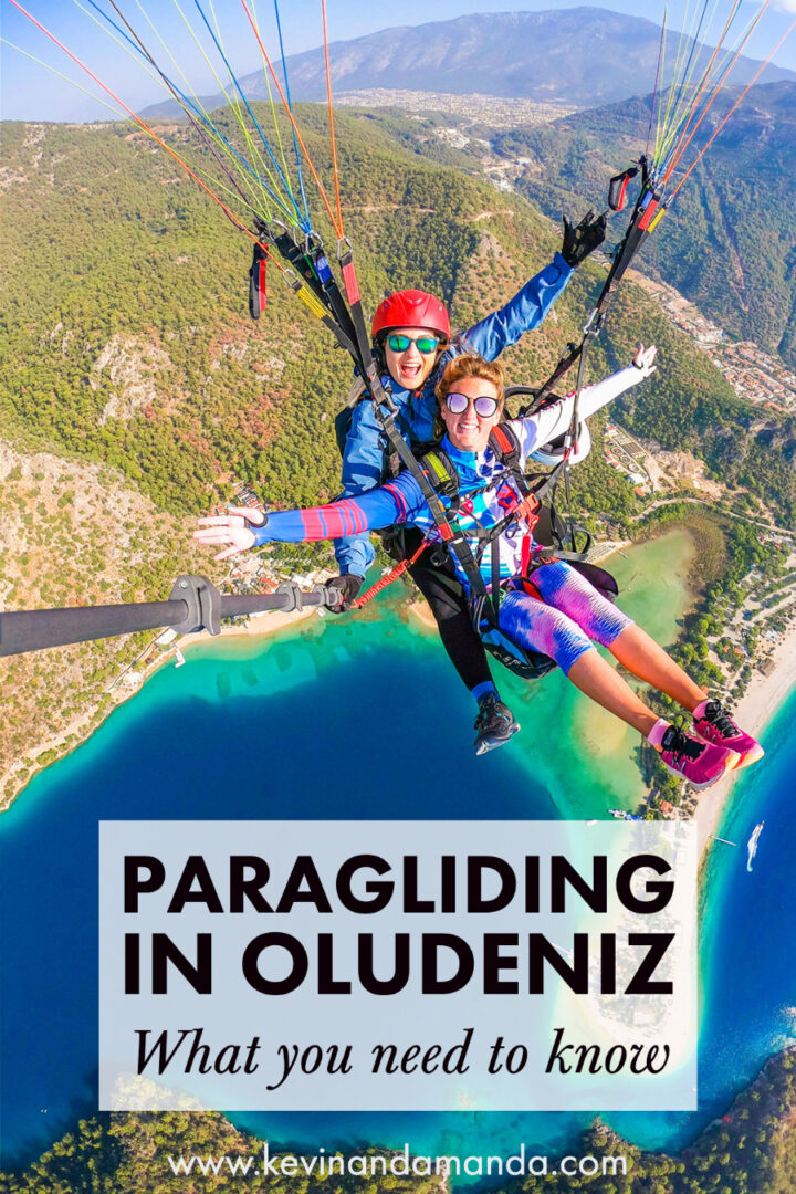 Two girls tandem paragliding over a turquoise blue lagoon and beach