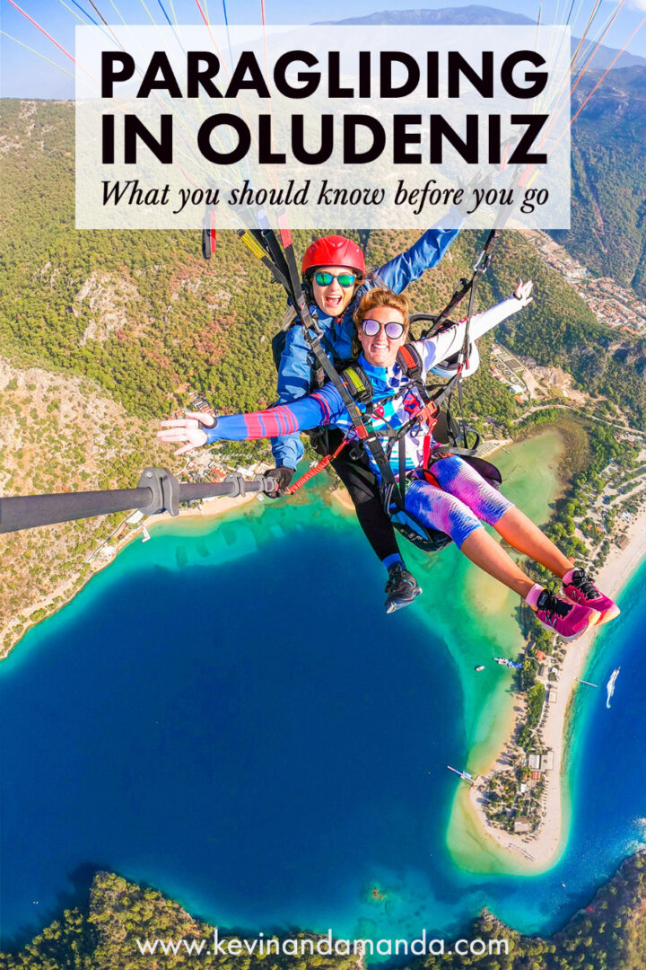 Two girls tandem paragliding over a turquoise blue lagoon and beach